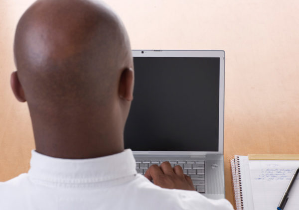 Man sitting in front of computer to demonstrate doing mindfulness exercise while at work