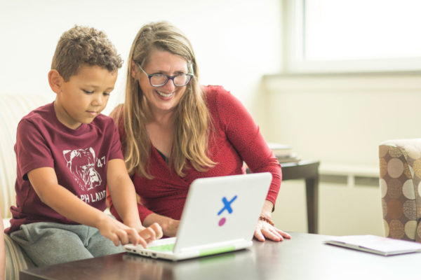 A Woman Sits Behind A Computer With A Young Boy Demonstrating Options For Improving The Interactions Children With Incarcerated Parents Have During Jail Visits