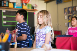 Photo of young girl meditating in classroom by Finn Ryan