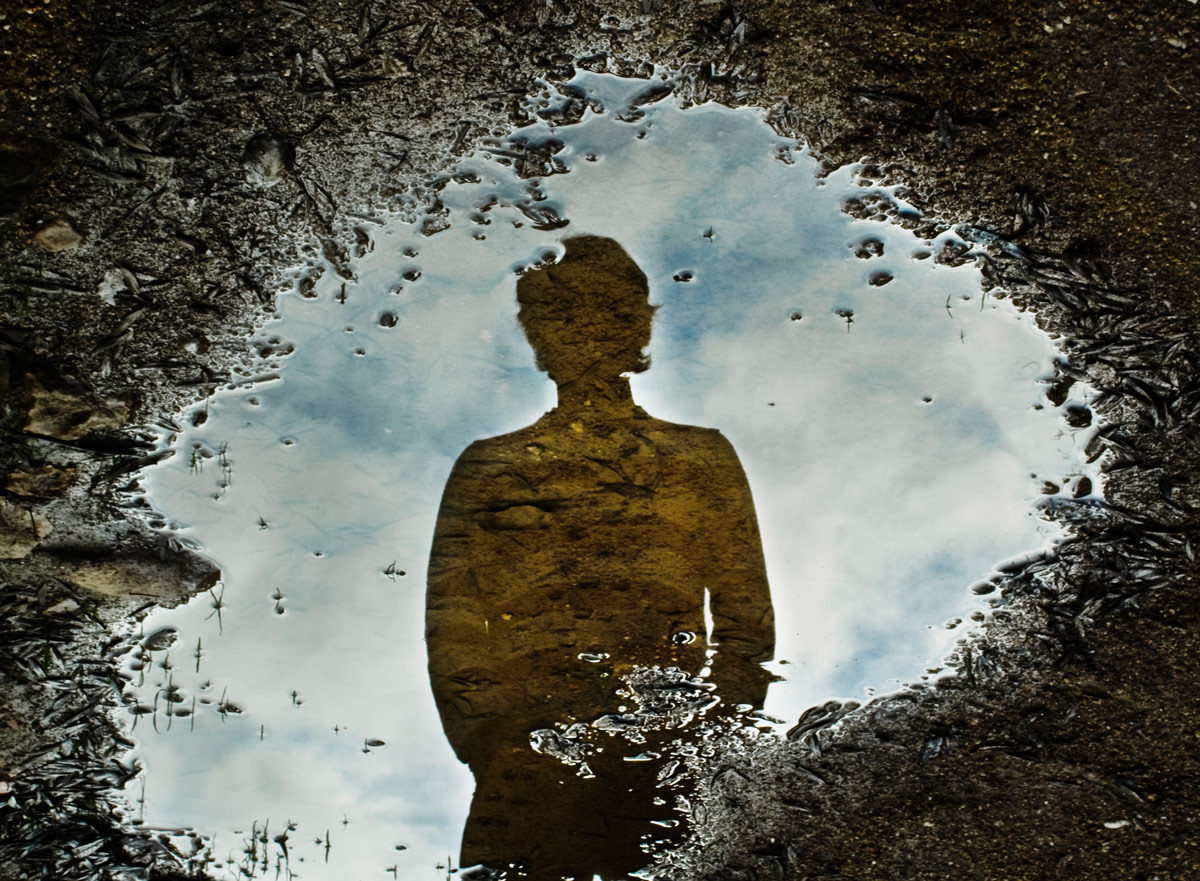Photo of reflection of person in puddle by micaelnuss via iStock